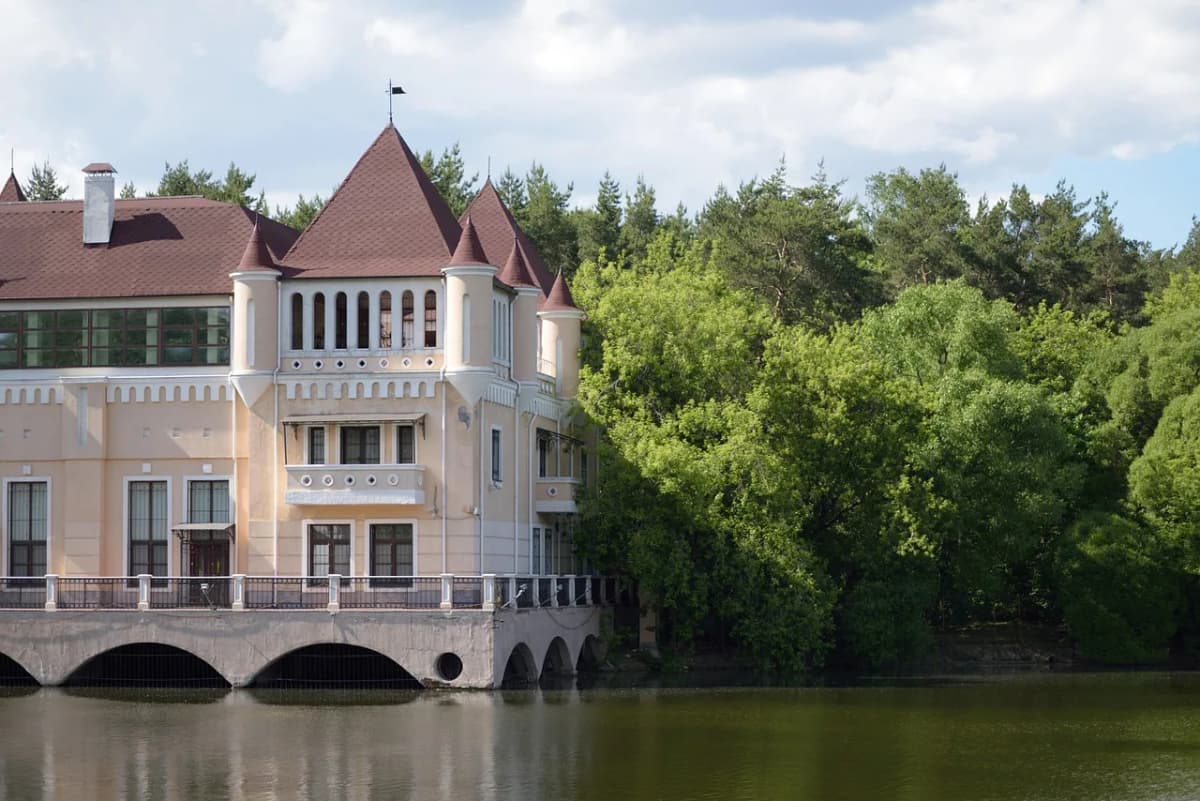 Historic countryside manor beside a lake, framed by dense forest, evoking the Lithuanian gentry setting of Pan Tadeusz