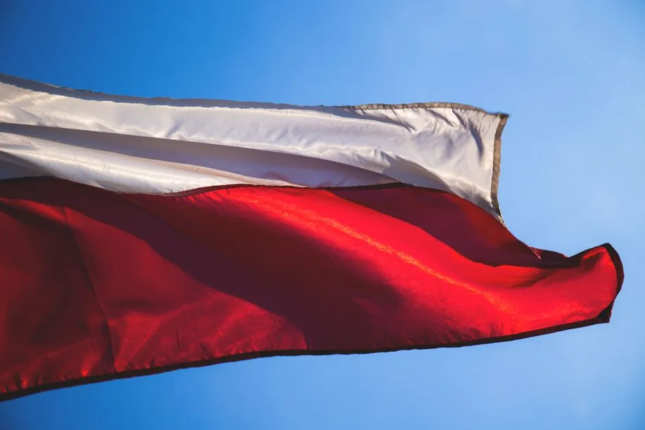 Polish flag waving against a blue sky, representing famous Polish people in sports, science, and the arts