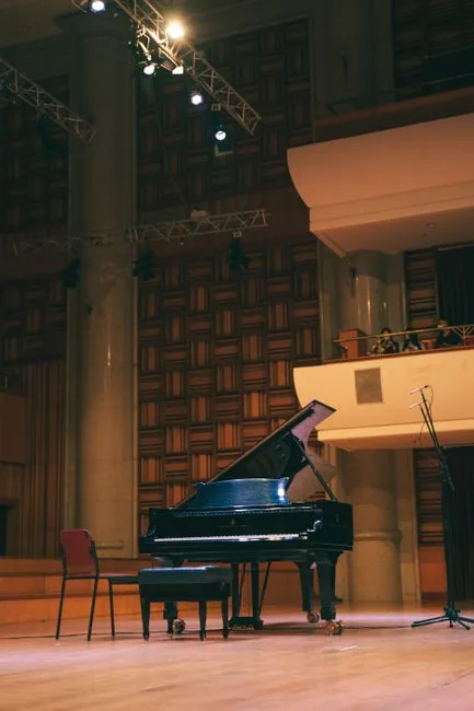 Empty grand piano on a concert hall stage under stage lighting