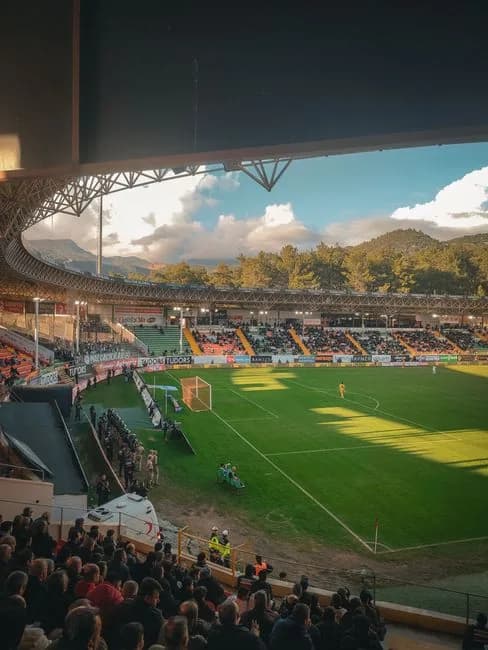 Football stadium at sunset filled with spectators watching a match