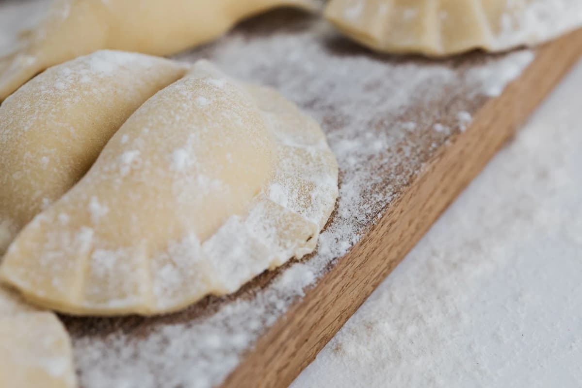Freshly made pierogi dusted with flour on a wooden board — Photo by kaboompics on Pexels
