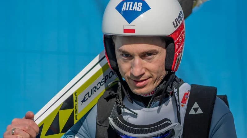 Kamil Stoch wearing a helmet with the Polish flag, holding his skis before a competition