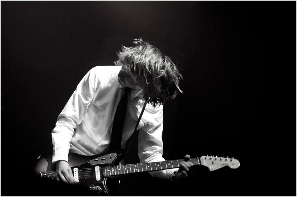 Antoni Budziński, the musician behind Klimt, performing live on electric guitar in dramatic black-and-white lighting