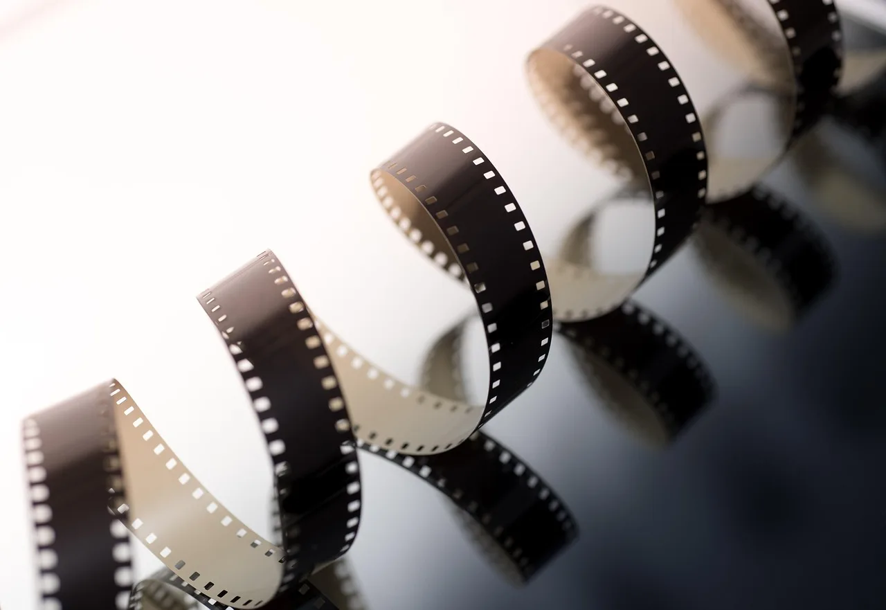 Spiral of black-and-white 35mm film reel against a reflective dark surface