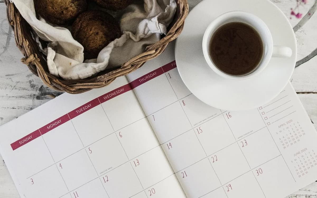 An open weekly calendar planner next to a cup of coffee, used to block out a study schedule