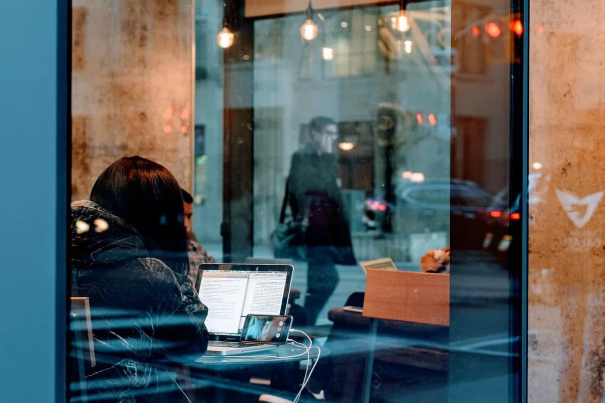 A person taking an online video lesson, laptop open and phone propped up for the call