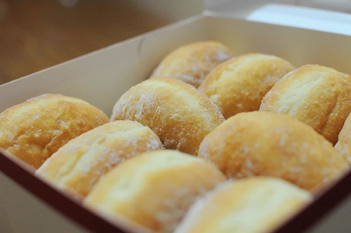 A bakery box filled with a dozen powdered paczki donuts, ready for Fat Thursday
