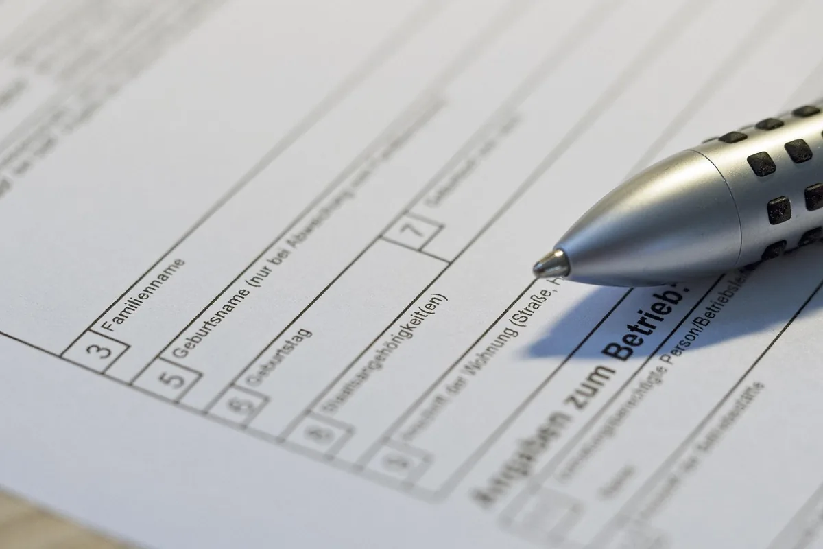 Filling out a paper application form with a pen, the kind of bureaucratic form used for PESEL applications