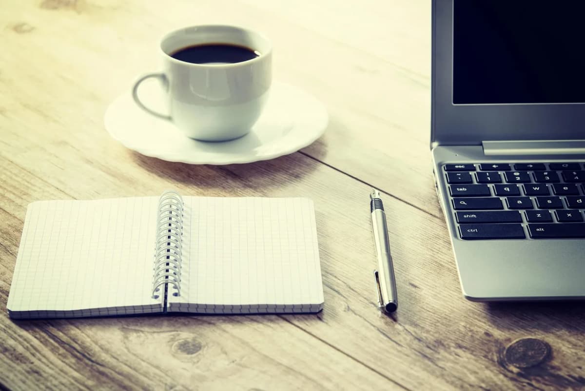 An open notebook next to a laptop and coffee, ready for jotting down Polish diminutives to remember