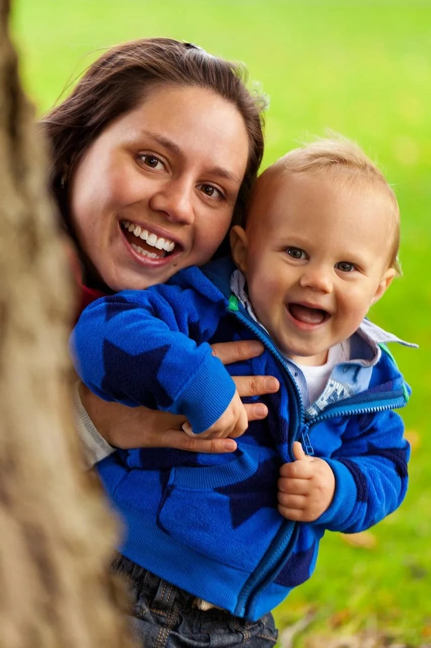 A mother laughing with her young child outdoors