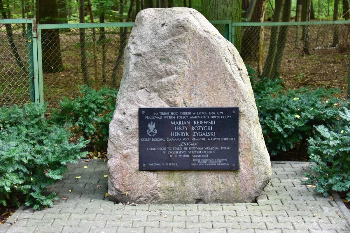A stone memorial plaque in a forest honoring the three Polish Enigma codebreakers