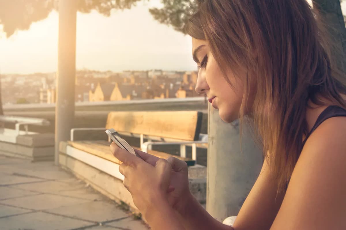 A young person texting on a smartphone outdoors