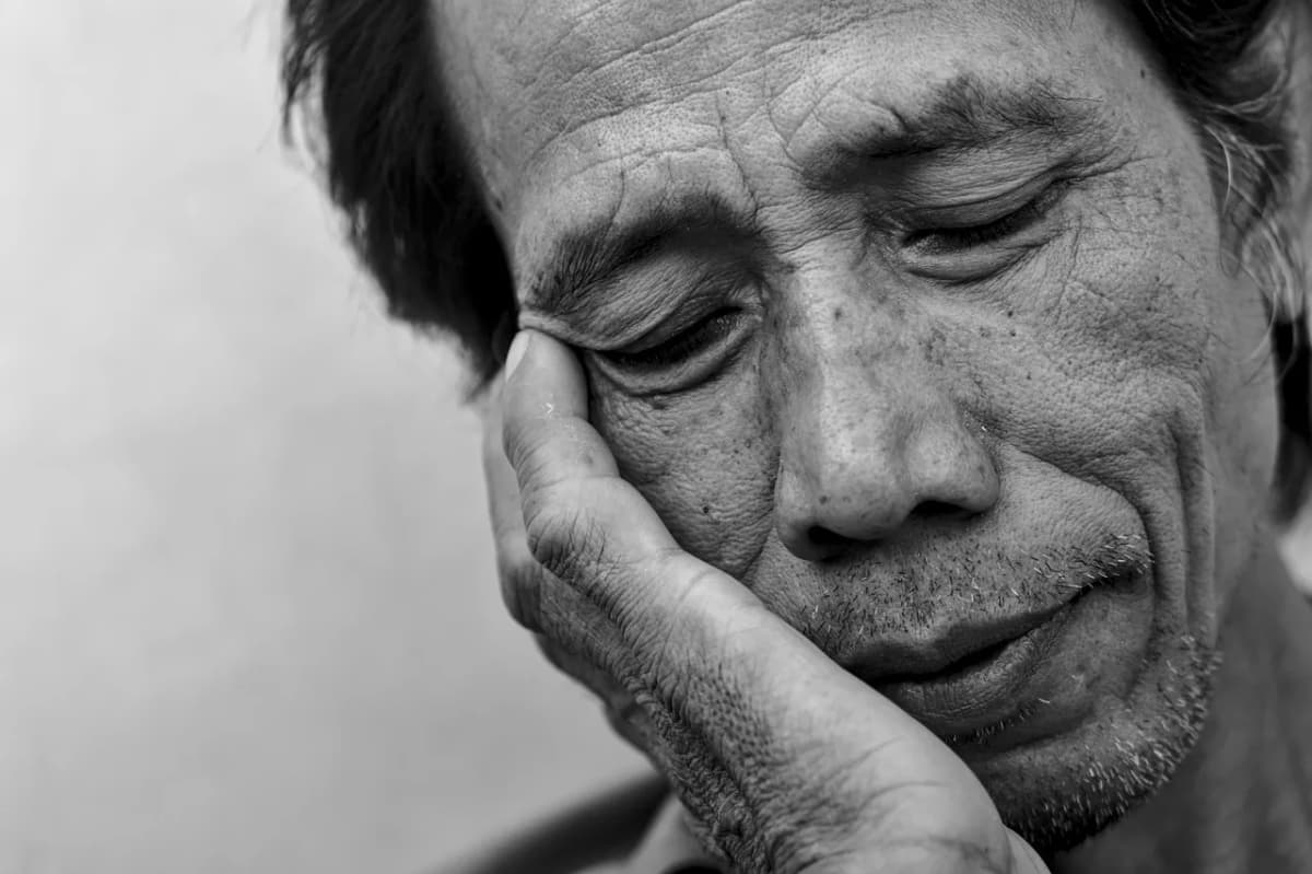 A close-up portrait of an exhausted man resting his head in his hand