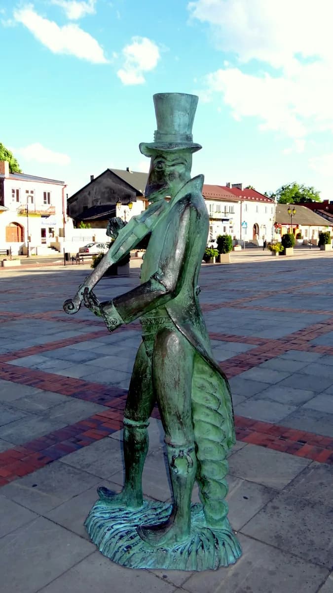 Another angle of the beetle statue in the market square, showing the surrounding buildings and paved plaza of Szczebrzeszyn's town center