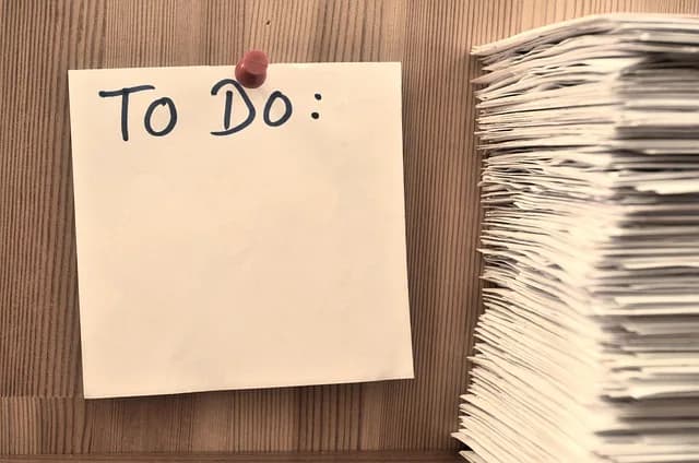 Handwritten "to do" note next to a stack of papers, representing completed versus pending tasks