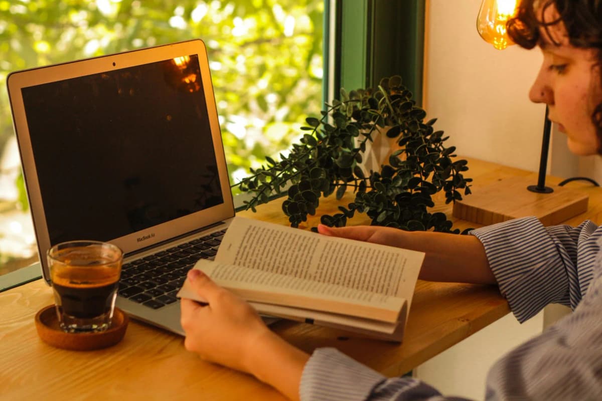 Cozy workspace with laptop, coffee, and book for daily study — Photo by Esra Saltürk on Pexels