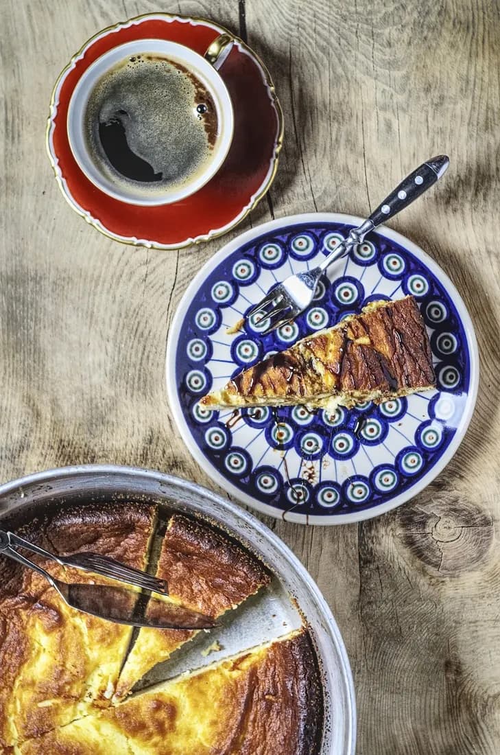 A golden-baked slice of sernik, Poland's traditional cheesecake, served with coffee