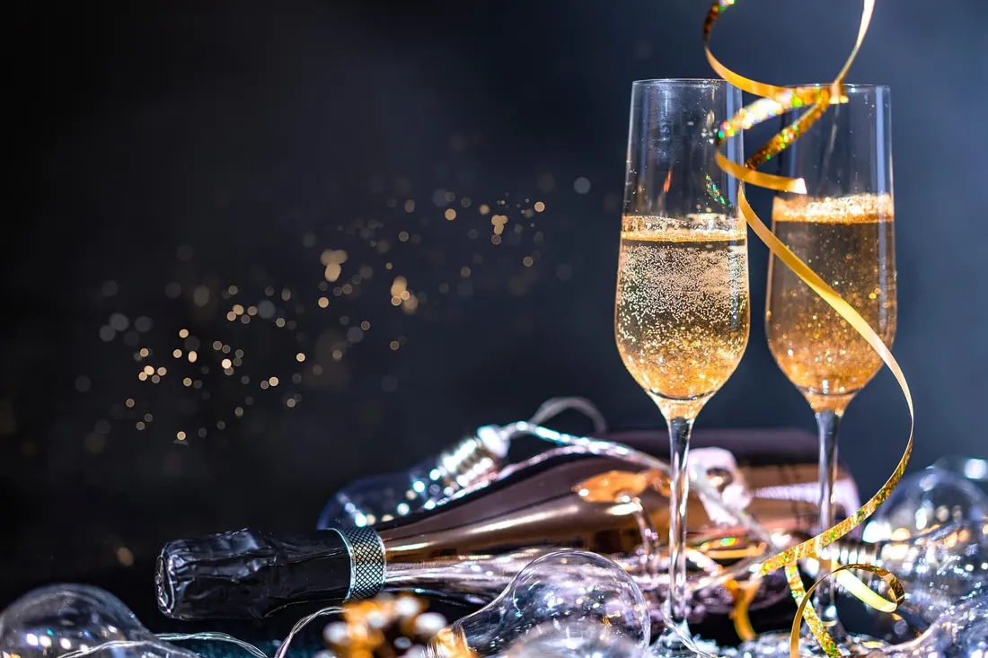 Champagne glasses being raised in a toast at a nighttime celebration