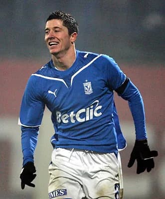 A young Robert Lewandowski celebrating a goal in a Lech Poznań kit, wearing a "BetClic" sponsored jersey, during a match in November 2009