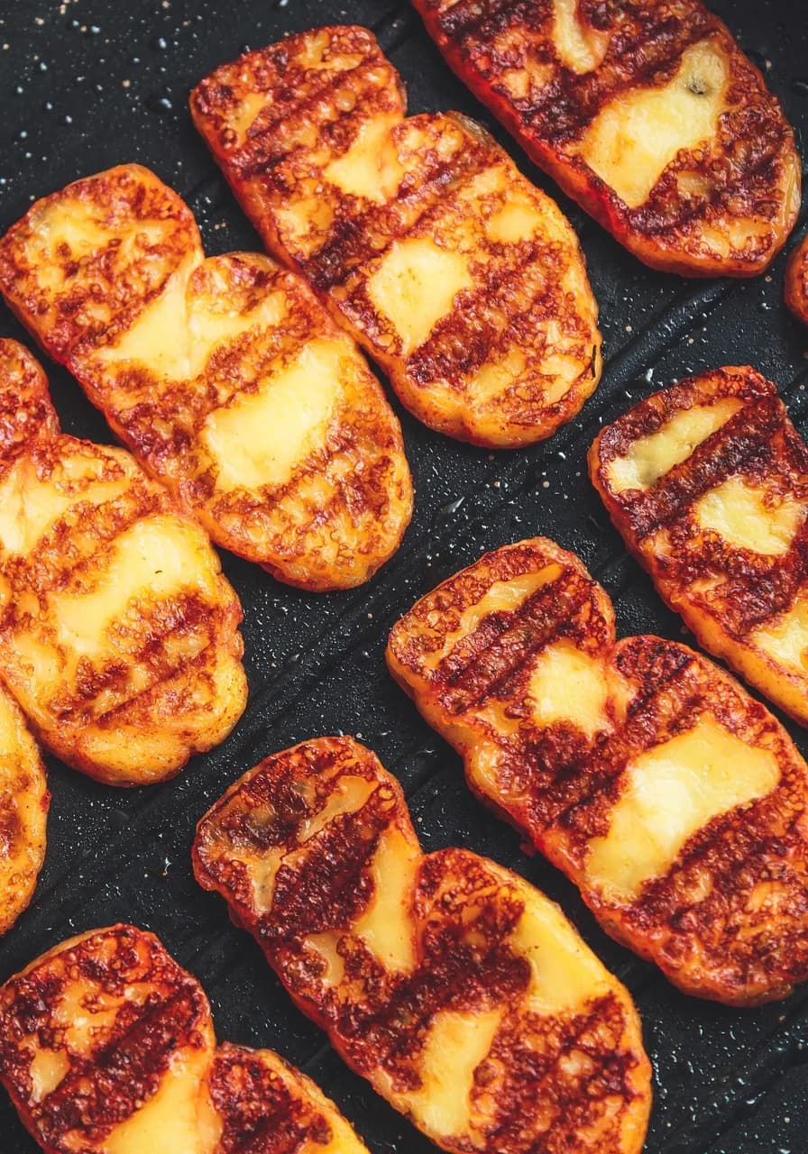 Golden, grill-marked cheese slices fresh off the pan — the same pan-frying technique used to prepare oscypek before it's topped with cranberry sauce