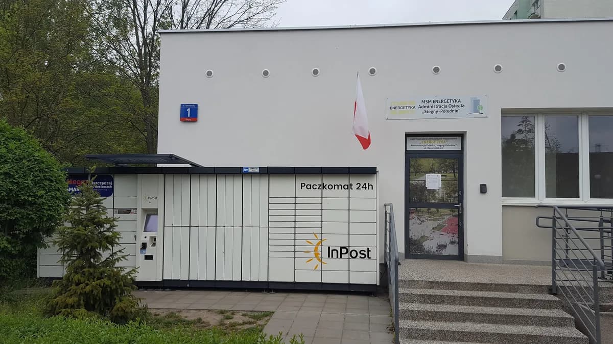 An InPost Paczkomat locker installed directly outside the entrance of a residential apartment building in Warsaw's Stegny district