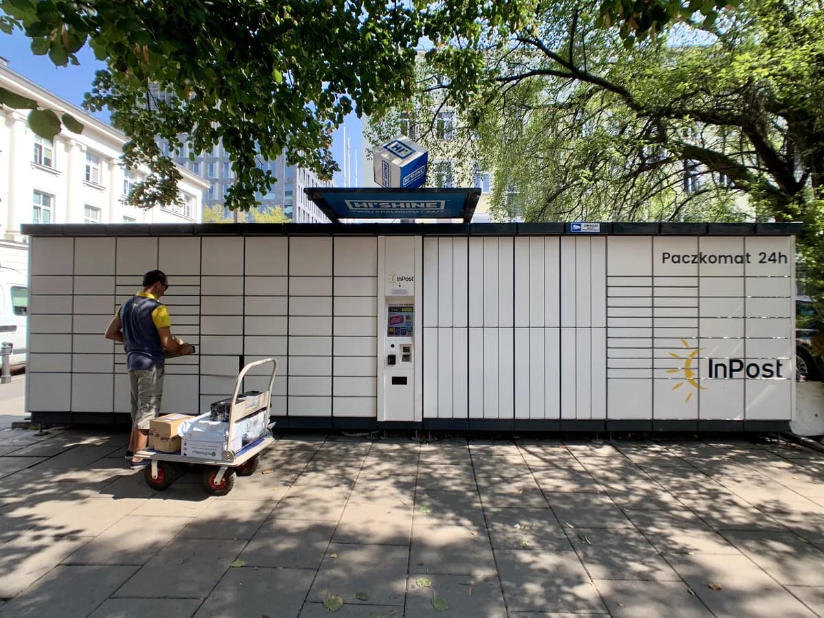 An orange-and-white InPost Paczkomat parcel locker on a street in Warsaw, Poland