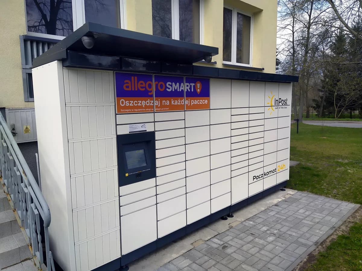 A single InPost Paczkomat locker standing in the rural Polish village of Osuchów, surrounded by grass and trees with no other buildings nearby