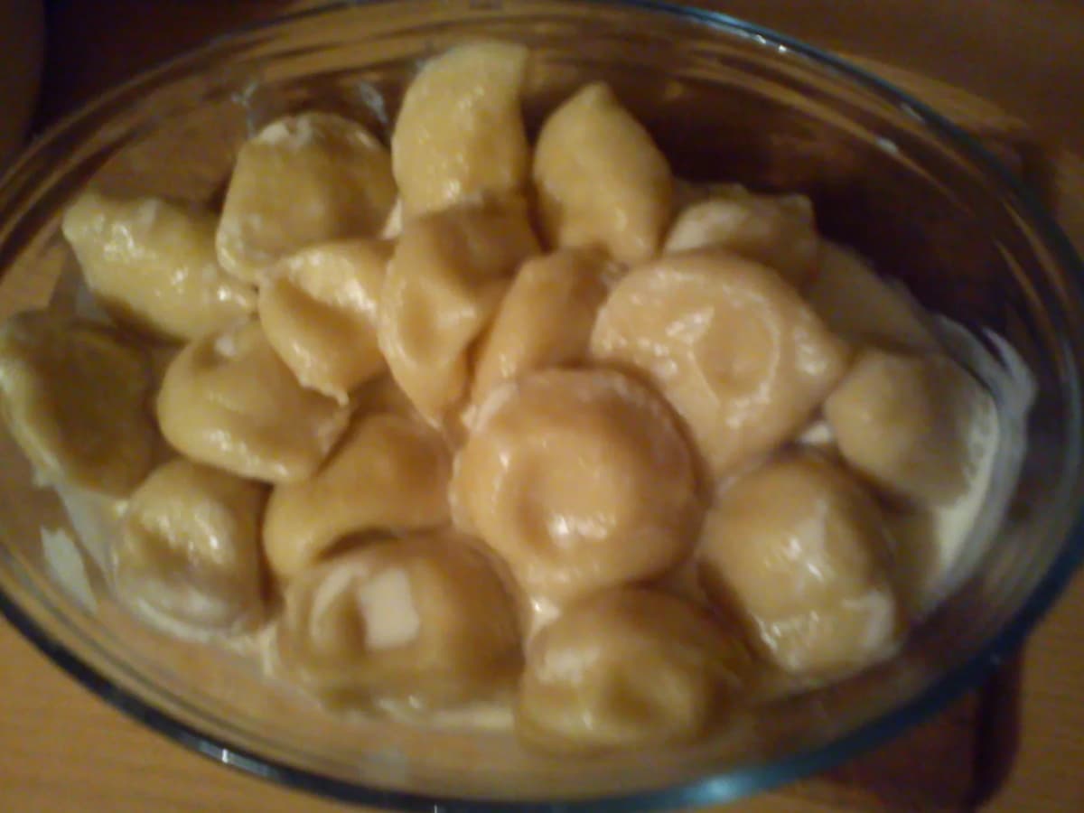 A plate of pierogi ruskie served in cream sauce, a traditional Polish filling of potato and cheese