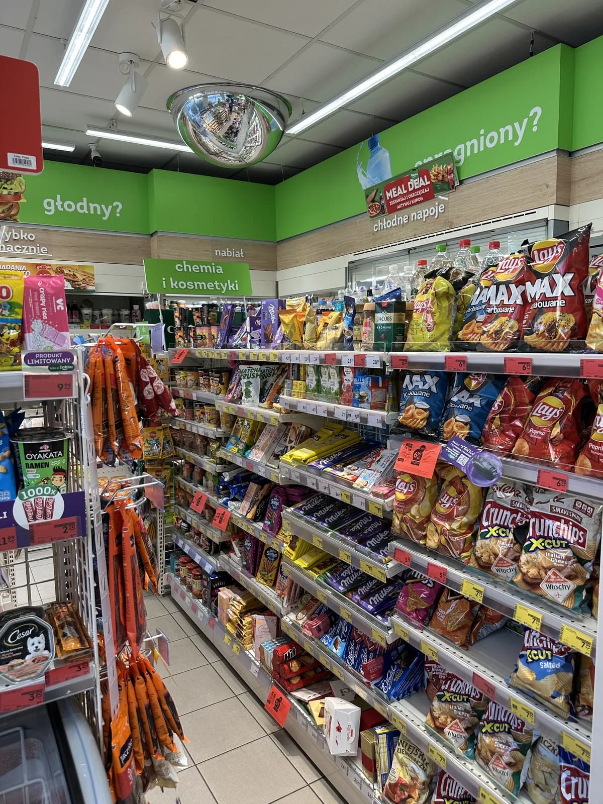 Shelves of chips, chocolate bars, and cookies inside a Żabka aisle, showing the snack selection
