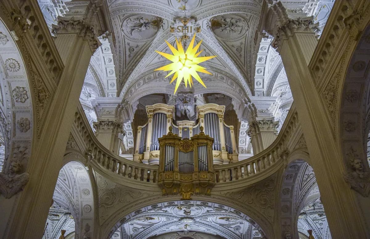 The ornate interior of a Catholic church, lit by a star-shaped ornament for the Christmas season