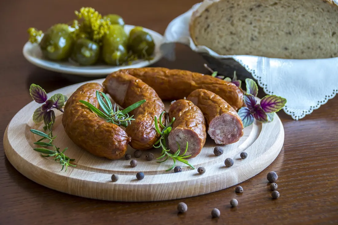 Coiled Polish kiełbasa sausage served with fresh herbs, peppercorns, and pickles, a traditional presentation