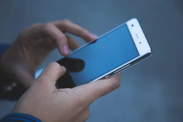 A close-up of two hands holding and using a smartphone