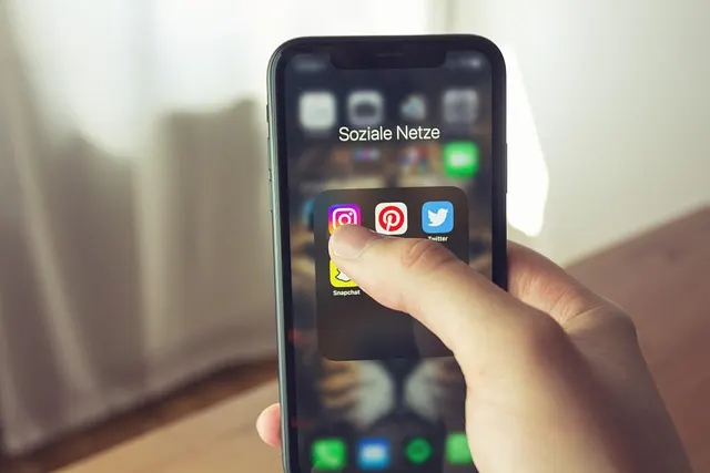 A close-up of a hand holding a smartphone and tapping an app icon on the screen