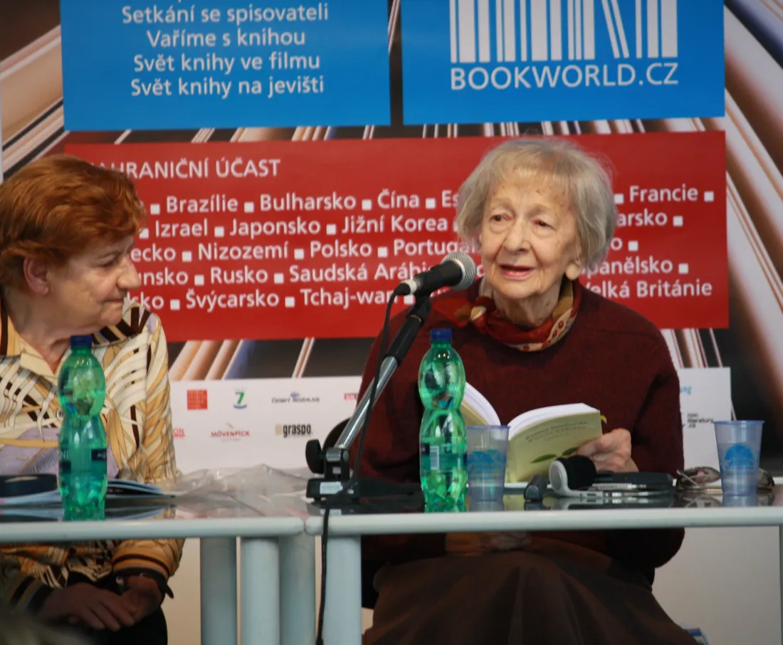 Wislawa Szymborska reading from a book at a microphone at the Prague Book World literary festival in 2010