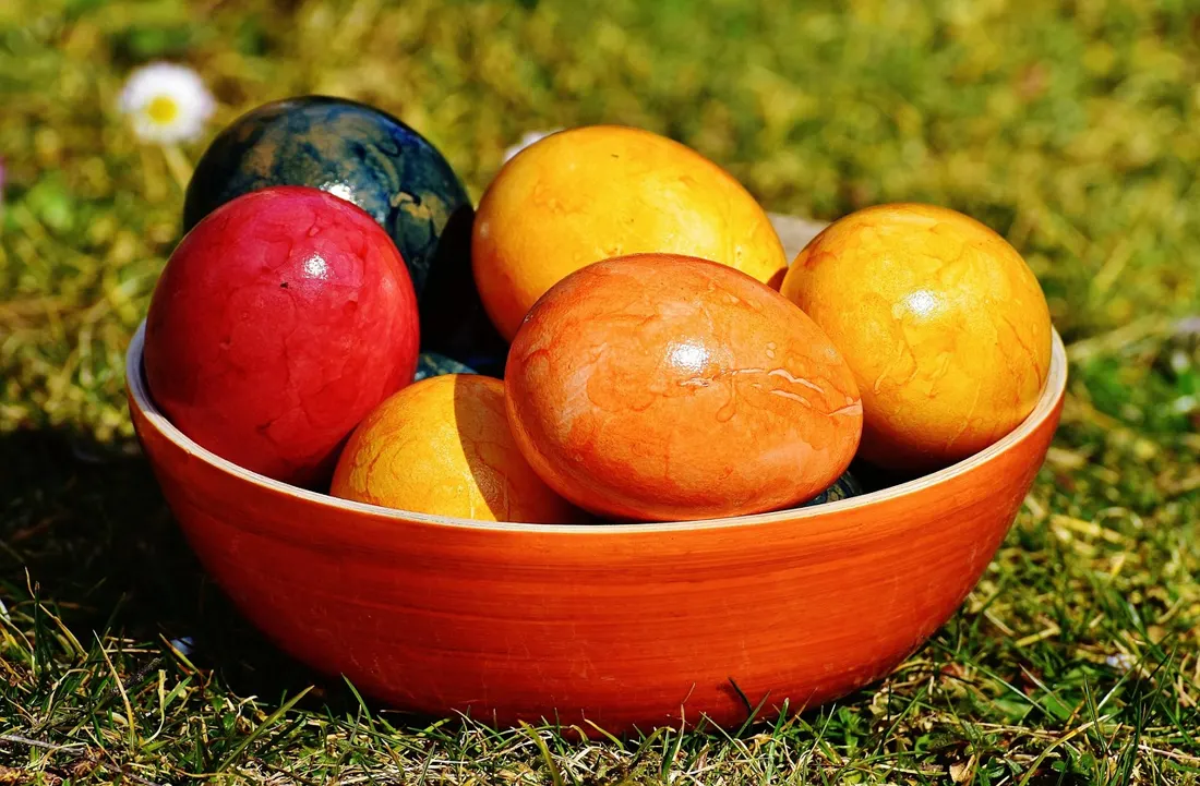 A bowl of solid-color dyed Easter eggs in red, orange, yellow, and blue, similar to Polish kraszanki